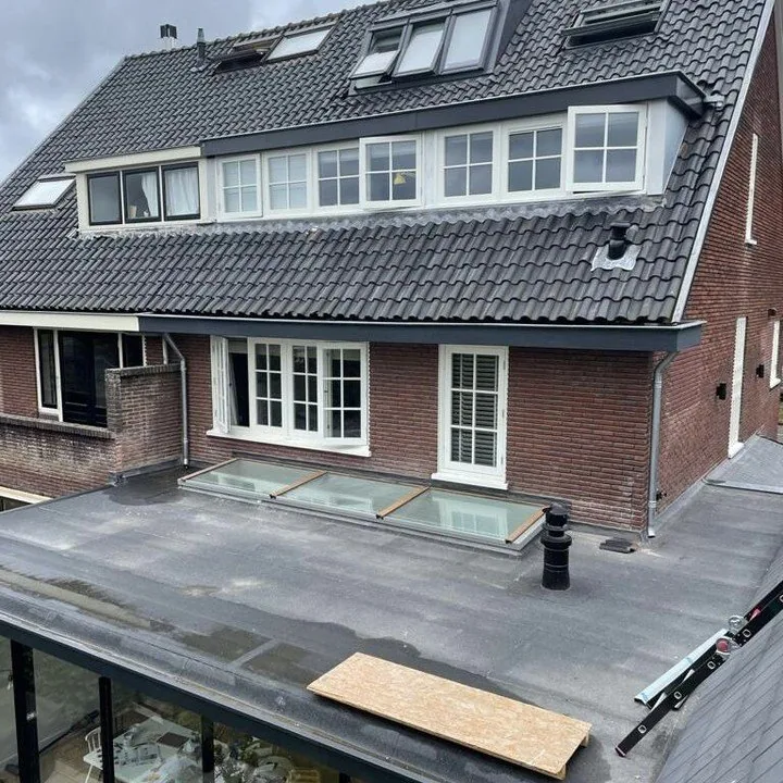 Dakwerk aan een woning met uitbouw